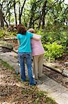 Teen girl helping senior woman walk through the park.  Vertical view with room for text.