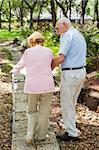 Senior couple out for a walk.  The husband is helping his wife with her walker.