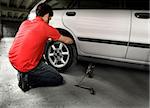 A male chaning a tire on a car in a garage
