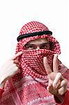 Portrait of an arabian young man in traditional headscarf - shemagh. He shows peace sign by hand.