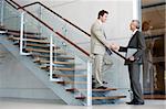 Two business men standing on a staircase shaking hands