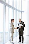 Two business men standing in a modern office building shaking hands