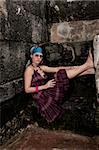 Portrait of young trendy female sitting on grunge background