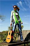 Fashion woman posing with a guitar on a beautiful sunny day