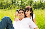 Young couple outdoors, woman taking photo with mobile phone