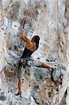Woman climbing on limestone rock in thailand