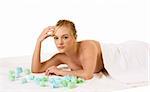 Attractive young female relaxing in spa surrounded by aromatherapy items