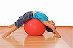 Happy little boy stretching on a gymnastic ball - isolated