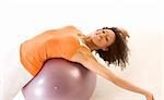 Dark skinned female stretching on exercise ball