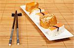 Sushi on the white plate and chopsticks on bamboo mat. Shallow depth of field