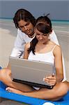 Romantic young couple working on laptop computer at the beach