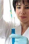 Female scientist at work in laboratory using a pipette and test tube.  Focus to pipette and test tube.