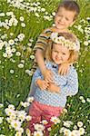 Little boy and girl on the daisy field hugging and posing for the camera