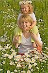 Happy laughing little girl with her mother on the flowers field