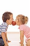 Little boy and girl bite into red apple - isolated feeding frenzy