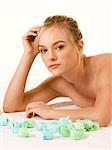 Attractive blonde young female relaxing in spa surrounded by aromatherapy items