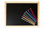 A empty black chalkboard with multicolored pencils. Isolated on white background