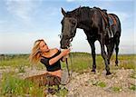 blond teenager and her black horse in a field