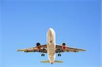 airplane flying overhead against a clear blue sky