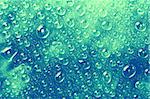 Blue-green water drops on a glass surface.