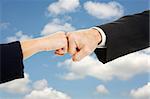 Female and male business hands doing a fist bump with sky for a background.