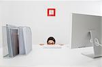 Young businesswoman hiding behind desk. Copy space