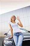 Young woman leaning on new car and similing