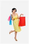 Mid adult Italian woman holding red shopping bags on white background