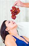 Close up portrait of nice young brunette getting tempted with grape