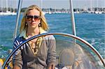 A stunningly beautiful young woman driving a powerboat on a sunny summer day.