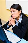 A woman employee is daydreaming in her office in front of the computer.