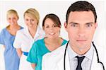 A male doctor with his team of colleagues out of focus behind him.