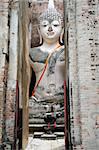 giant seated buddha amidst the ruins of an ancient temple in sukothai, northern thailand