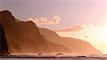 Receding headlands of Kauai coastline illuminated at sunset over a stormy sea with a distant bird