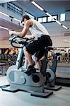 portrait of young man bicycling in gym.
