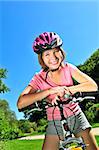 Portrait of a teenage girl on a bicycle in summer park outdoors