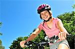 Portrait of a teenage girl on a bicycle in summer park outdoors