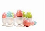 Polka dot easter eggs in cups on white background