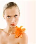 great portrait of a blond girl with wet hair and an orange lily on her shoulder