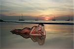 Woman lying on the sand beach at sunset