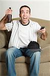 A young sports fan holding a beer is cheering because his team scored