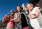 Portrait of three trashy women outdoors making a rude hand gesture