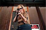 Blonde woman on her front porch with a rifle