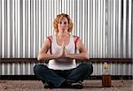 Woman meditating with cigarette and tequila bottle