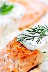 Cooked salmon fillets with dill sauce on white plate