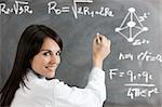 portrait of mid adult woman writing chemical formula on blackboard