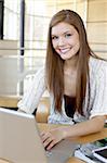 Smiling Girl at table studying in university commons area.