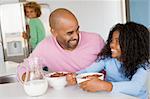 Father Sitting With Daughter As She They Eat Breakfast With Her