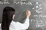 portrait of mid adult woman writing chemical formula on blackboard