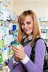 Portrait of blonde woman choosing shampoo in pharmacy.